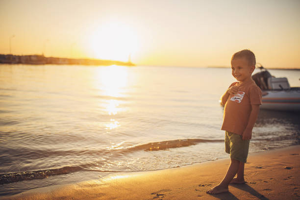 Little boy standing on the beach by the sea.