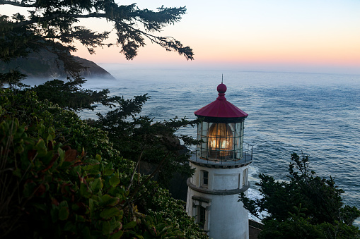Sun rises over the Pacific Ocean on a foggy day at the Heceta Lighthouse near Florence, Oregon in the Pacific Northwest.