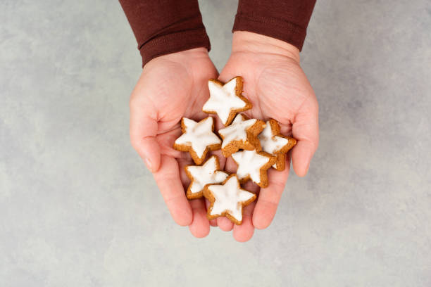 stelle alla cannella, biscotti natalizi tradizionali tedeschi zimtsterne tra le mani, pan di zenzero con spezie all'anice per le feste - zimtstern foto e immagini stock