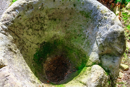 Top view of an old stone washbasin over a cobblestone floor during the day