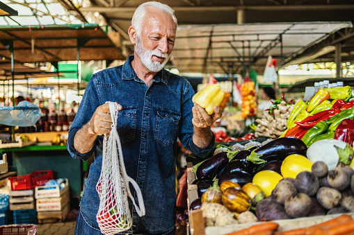 Senior man shopping at the farmer's market. One elderly man buying a fresh vegetable at a community marketplace.