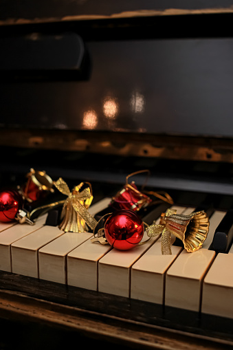 old Piano keyboard decorated with a bauble, bells and toy drums. preparing for christmas and new year and decorating house. close up, copy space