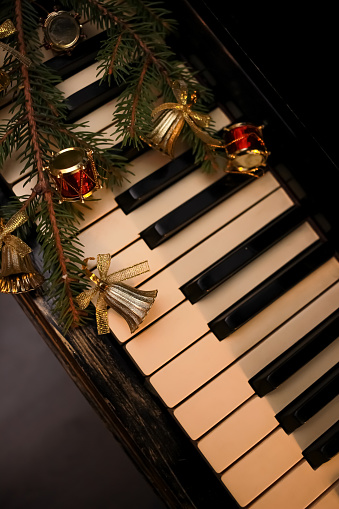 old Piano keyboard decorated with a fir branch, bells and toy drums. preparing for christmas and new year and decorating house. close up, flat lay, copy space