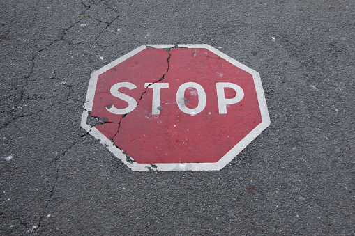stop sign floor paint white red text painted on black asphalt street