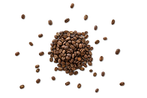 Closeup of a pile of organic whole roasted coffee beans isolated on a white background from above, top view