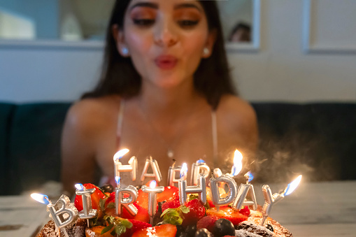 Young woman blowing out the candles on her cake