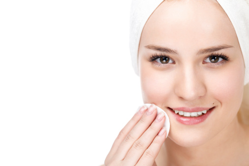 Beauty portrait of a young woman removing makeup from her face. Isolated against white background.