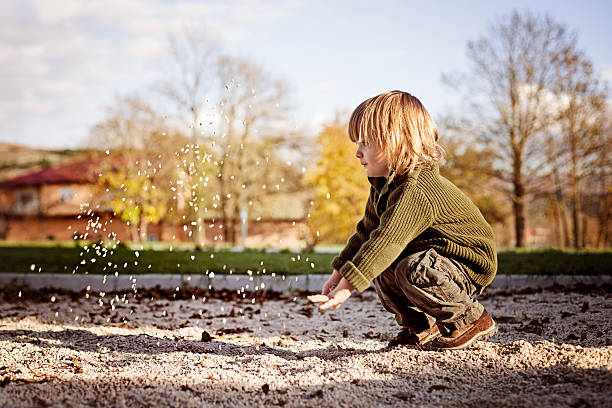 kleine junge werfen sand entfernt - sandbox child human hand sand stock-fotos und bilder