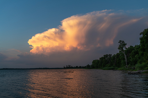 Large cloud with orange hue during sunset at North Turtle Lake in Minnesota, USA.