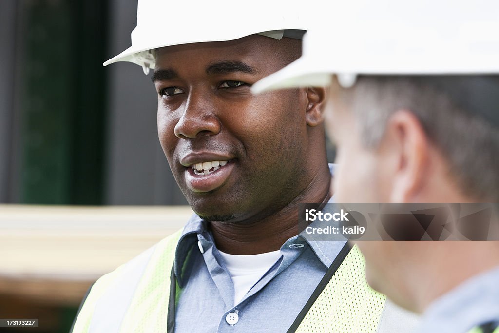 Close-up di colleghi con hardhats e sicurezza e giubbotti - Foto stock royalty-free di Ambientazione esterna