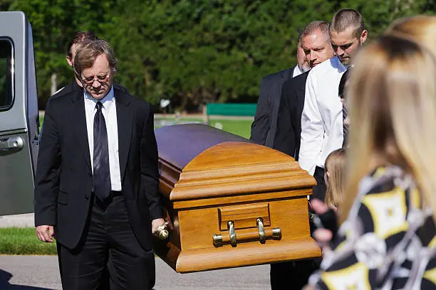 A group of men carrying a casket in a funeral.