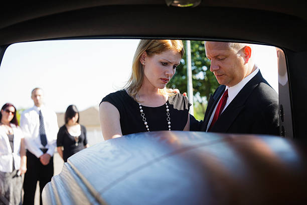 Grieving Couple A grieving couple standing at the rear of a hearse looking down at the casket.  Taken from within the hearse. hearse photos stock pictures, royalty-free photos & images