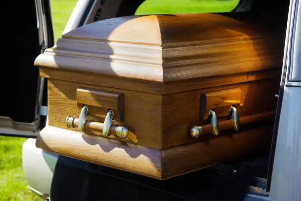 A casket in the back of an open hearse.