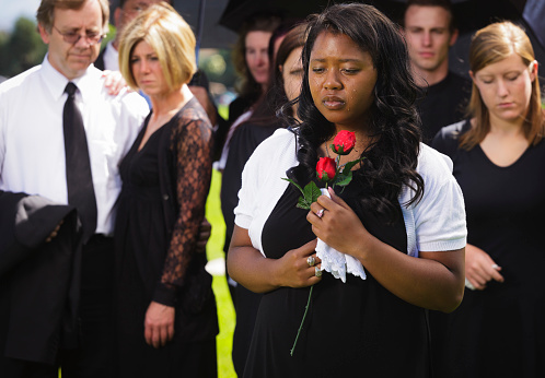 A grieving woman standing graveside at a funeral.