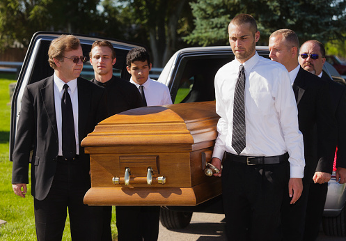 A group of men carrying a casket in a funeral.
