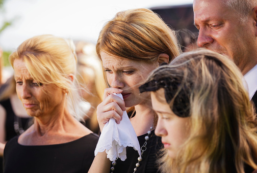 A grieving family standing graveside at a funeral.