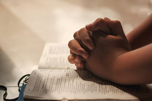 Christian Religion concept background. Hands folded in prayer on a Holy Bible