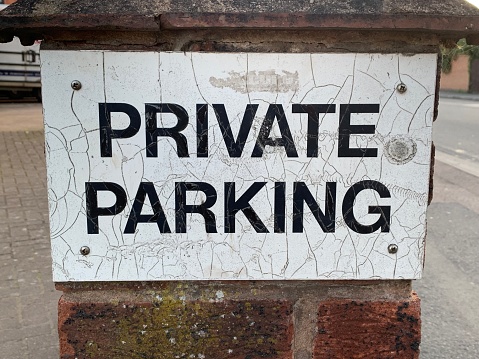 Up close picture of a old weathered private parking sign attached to a brick wall
