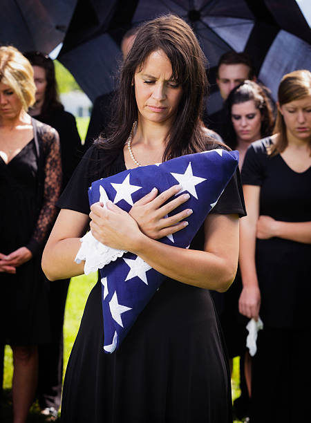 mujer sosteniendo una bandera de funeral - graveside service fotografías e imágenes de stock