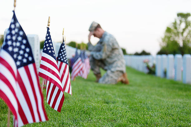 Soldier kneeling at grave American soldier kneeling at a veterans grave on memorial day. Focus on the foreground. us memorial day photos stock pictures, royalty-free photos & images