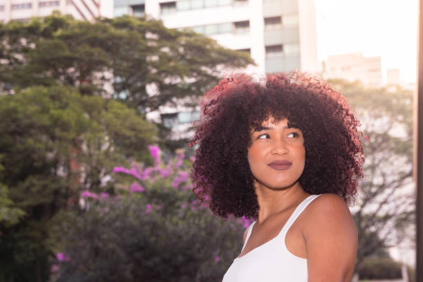 mujer mirando a un lado y sonriendo, cabello negro natural y árboles - frizzy 20s adult african descent fotografías e imágenes de stock