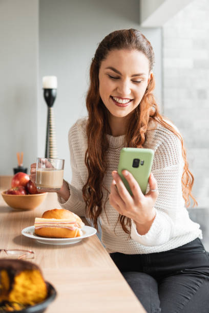 istock woman eating breakfast and using cell phone at home 1731991628
