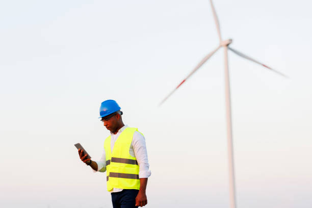istock Young Engineer wearing uniform ,helmet hold document inspection work in wind turbine farms rotation to generate electricity energy. 1732006380