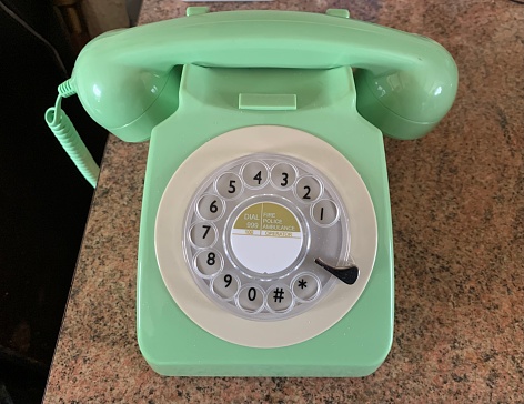 Picture of a vintage green rotary phone placed on a kitchen worktop, taken indoors