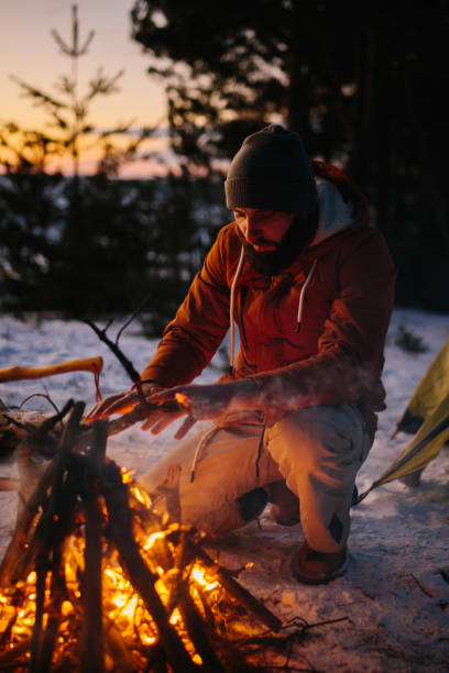 istock A man sits near a campfire, warming himself by the fire in a winter forest at sunset. 1732016376