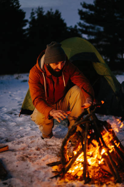 istock A man sits near a campfire, warming himself by the fire in a winter forest at sunset. 1732016378