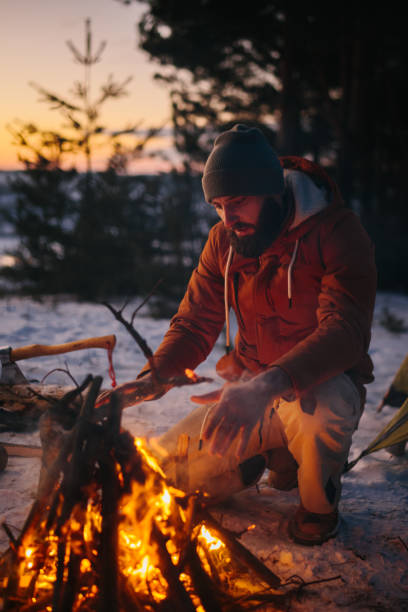 istock A man sits near a campfire, warming himself by the fire in a winter forest at sunset. 1732016885