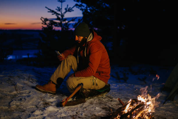istock A hiker checks his phone while warming himself by a campfire at night in the mountains. 1732016891