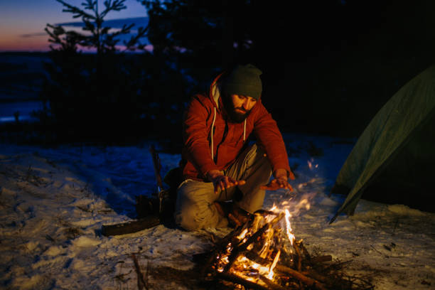 istock A man sits near a campfire, warming himself by the fire in a winter forest at sunset. 1732016897