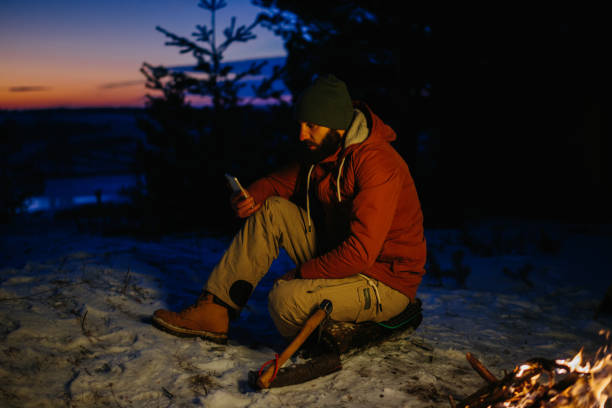 istock A hiker checks his phone while warming himself by a campfire at night in the mountains. 1732016900
