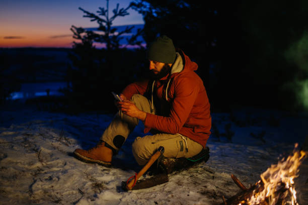 istock A hiker checks his phone while warming himself by a campfire at night in the mountains. 1732016902