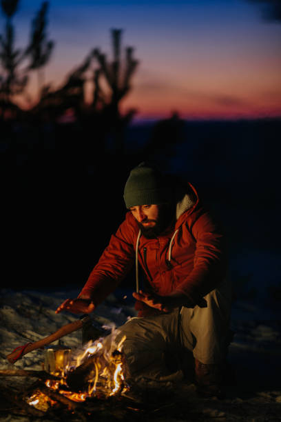 istock A man sits near a campfire, warming himself by the fire in a winter forest at sunset. 1732016924