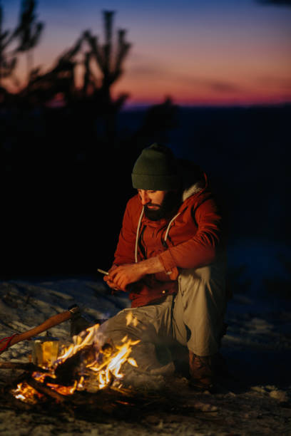 istock A hiker checks his phone while warming himself by a campfire at night in the mountains. 1732016932