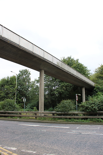 Concrete overhead public pathway overlooking a dual carriageway, taken on a cloudy day