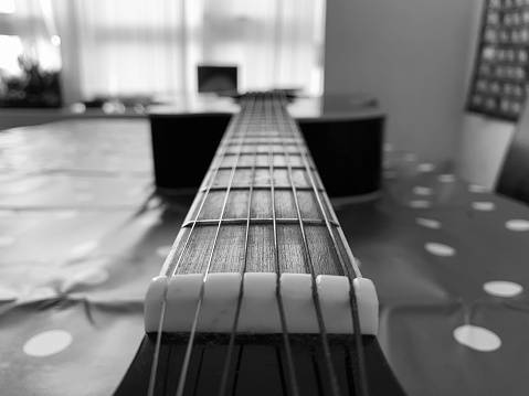 A 6 String acoustic guitar close up picture of the top of fret board, perspective focus