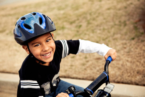 Riding bike Happy young boy riding his bike. long sleeved recreational pursuit horizontal looking at camera stock pictures, royalty-free photos & images