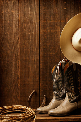 Cowboy boots, cowboy hat, and a lariat in a western setting.
