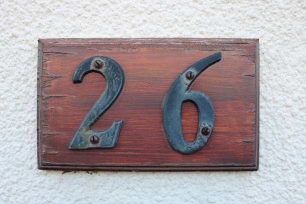 istock Black numbers 26 screwed onto a old wooden placard UK 1732049103