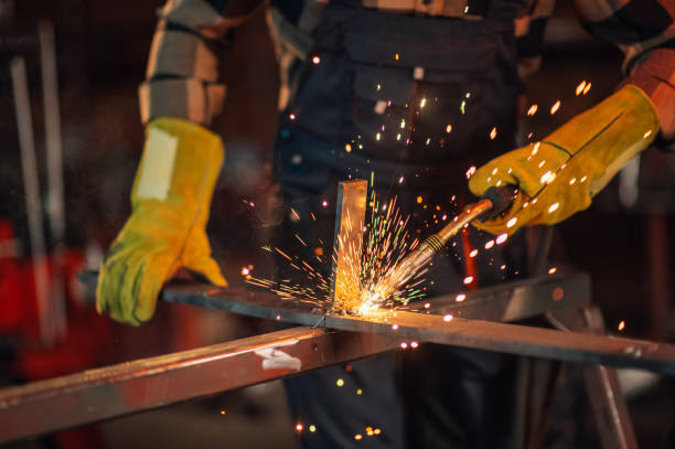 istock Glowing sparks flying all around the working facility as man welding. 1732049144