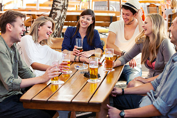 Friends drink and laugh while at a sidewalk cafe stock photo