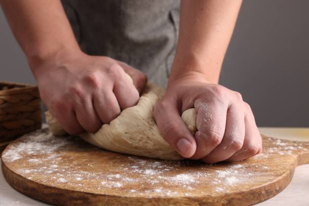 istock Man kneading dough at table near grey wall, closeup 1732099686