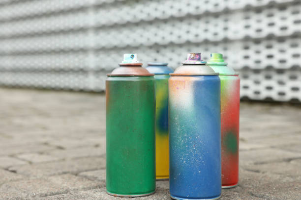 Used cans of spray paints on pavement, closeup