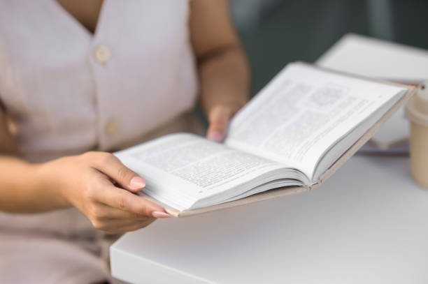 istock Woman reading book at white table outdoors, closeup 1732127245