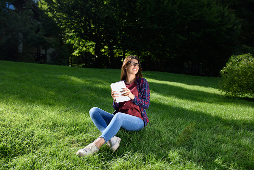 Young woman with book in park on sunny day