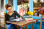 Female college student Studying and writing something while sitting in cafe