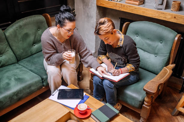 Female college students spending time studying together in coffee shop